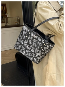 Detail of floral embroidery and metal rivet fixings on a black leather tote shoulder bag