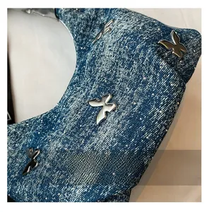 Close-up of blue denim cloud bag with silver butterfly charms and sparkling rhinestones