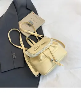 Detail of elegant cream yellow bucket backpack with lace trim and bow on blazer background
