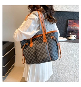 Detail of checkered tote bag with brown leather handles and matching small zip pouch