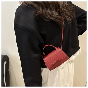 Model wearing a red crocodile pattern mini crossbody bag with a modern handle and strap