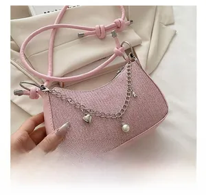 Detailed view of pink glitter crescent bag featuring silver chain with heart and star charms