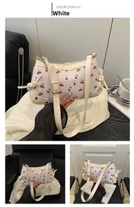 Detail view of white shoulder bag with cherry print and side bow tie decoration
