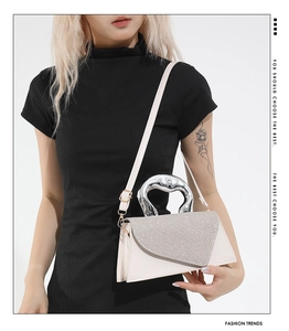 Detail of cream white shoulder bag featuring sparkling rhinestones and a silver metal handle