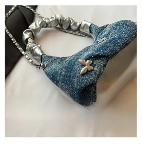 Close-up of blue denim and silver fabric handbag with butterfly buckle and sequins