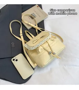 Detailed view of yellow faux leather backpack with lace trim and bow knot detail