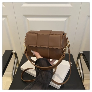Close-up of brown woven leather crossbody bag with wave edge flap and gold chain detail