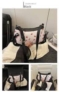 Detail of white shoulder bag with cherry print and black decorative side ribbons