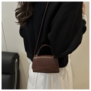 Détail de la texture crocodile marron vintage sur un petit sac à bandoulière tendance