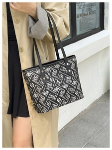 Close-up of black tote bag featuring white floral embroidery and geometric patterns