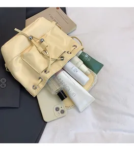 Top view of cream yellow bucket backpack showing spacious interior with cosmetics and phone