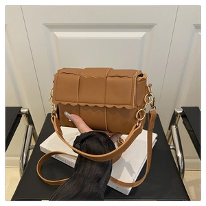 Detail of caramel woven crossbody bag featuring thick padding and wavy edge flap