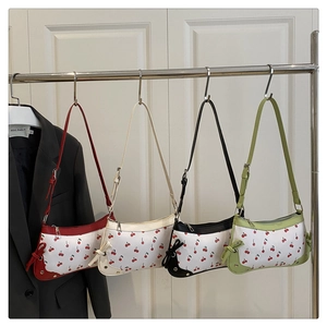 Detail view of four cherry-printed underarm bags with ribbon bows in multiple colors
