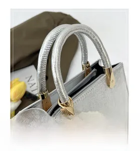 Detail of silver glitter handbag featuring golden hardware and a large pearl charm