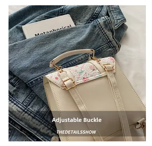 Detail of adjustable metal buckle and floral flap on creamy white campus backpack