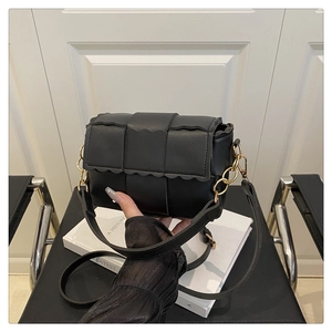 Detail of black woven leather crossbody bag with gold chain and wavy flap edge