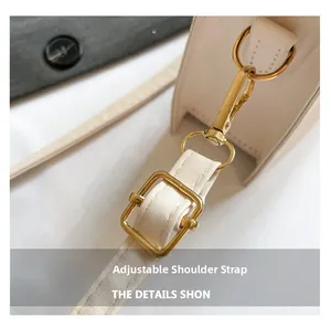 Detail of adjustable white leather shoulder strap with gold metal buckle and spring hook