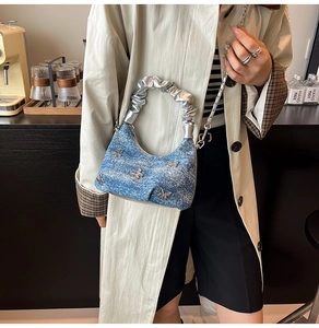 Detail of blue denim shoulder bag with silver butterfly charms and ruched cloud handle