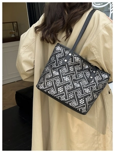 Detail of embroidered tote bag with geometric patterns on a trench coat model