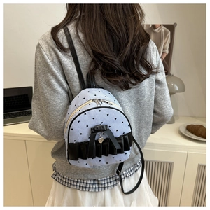 Polka dot mini backpack with bow detail and silver heart pendant on model