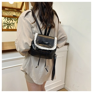 Close-up of the black leather backpack featuring white lace trim and a delicate bow detail