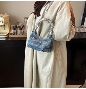 Detail of blue tweed handbag with silver butterfly ornaments and pleated metallic handle