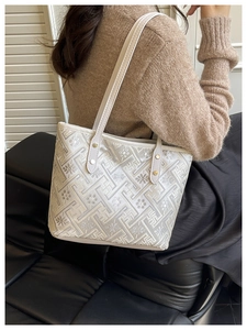 Close-up of elegant white tote bag with floral embroidery and Greek key patterns