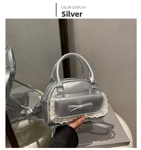 Detail of silver bowling bag featuring lace trim, bow decoration and metallic finish