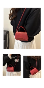 Detail of red crocodile embossed mini crossbody bag shown worn over black hoodie