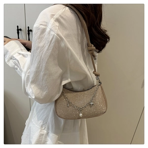 Détail du sac pailleté champagne avec chaîne métallique et breloques perles et étoiles