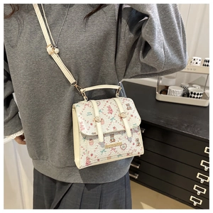 Detail of cream flap bag featuring cute cartoon animal prints and pearl buckle straps