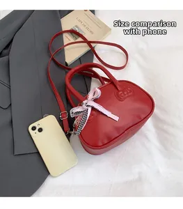 Size comparison of a red bow mini handbag next to a smartphone on a white surface