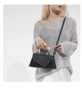 Detail of black leather handbag featuring glitter flap and silver horseshoe metal handle