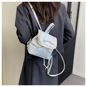 Detail of light blue bucket bag with white lace trim and bow on grey blazer