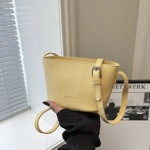 Chic yellow lychee texture bucket bag with adjustable strap shown in hand by window