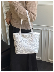 Detail of white jacquard tote bag with geometric patterns and metal rivet handles