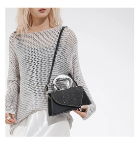 Detail of silver wavy metal handle and glitter flap on black leather crossbody bag