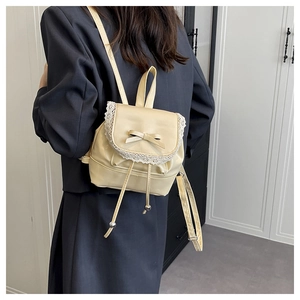 Rear view of model wearing a beige ballet style bucket backpack with lace and bow