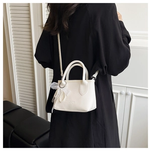 Close-up of white lychee leather square bag with lace pearl charm and fashion embossing