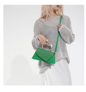 Detail of green sequined handbag featuring artistic silver wavy metal handle and fine stitching