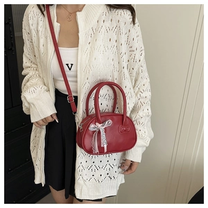Close-up of bright red crossbody bag featuring a checkered bow and lace detail