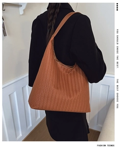 Close-up of caramel brown woven tote bag showing detailed interlaced leather texture