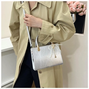Detail of silver metallic textured crossbody bag with decorative pearl bow charm