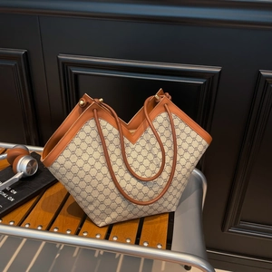 Classic V-shape monogram tote bag with brown leather trim on a wooden bench