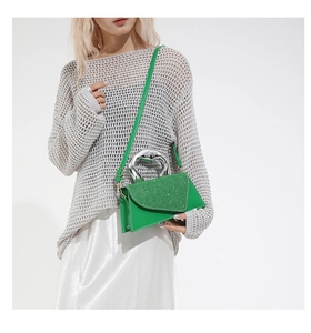 Close-up of vibrant green glitter handbag with metallic handle on a stylish model outfit