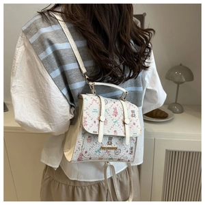 Detail of a white backpack with cute rabbit and bear prints and gold metal logo
