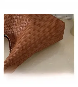 Detailed view of the brown leather woven pattern on the side of a retro shoulder bag
