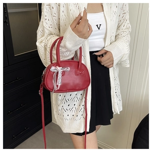 Detail of red leather bowling bag with bow decoration and adjustable shoulder strap
