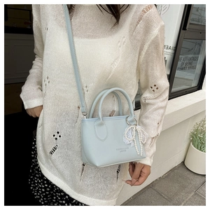 Detail shot of light blue mini square bag with lychee texture and pearl bow charm