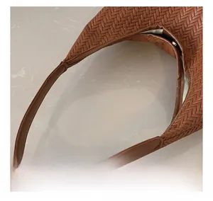 Close-up of woven brown leather shoulder bag handle showing fine stitching detail